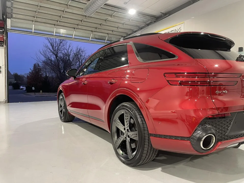 Red Genesis GV70 from the rear beside the open bay door